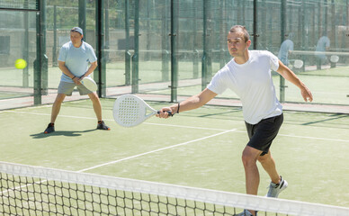 Wall Mural - Padel game - man with partners plays on tennis court