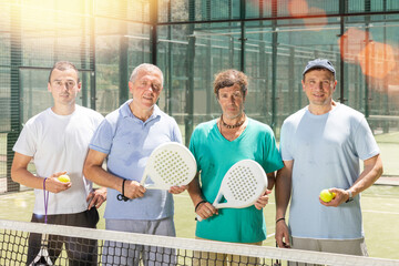 Wall Mural - Group of men posing with rackets and balls on padel tennis court