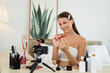 © InfiniteFlow - Young woman making beauty and cosmetic tutorial video content for social media. Beauty blogger smiles to camera while showing how to beauty care to audience or followers. Unveiling