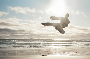 Poster - Beach, karate and man with training, kick and fitness with achievement, jump and practice. Active, routine and ocean with guy, lens flare and talent with exercise, hobby and martial arts for wellness