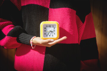 Wall Mural - Caucasian young woman holding a clock.