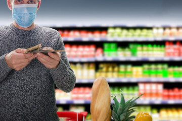 Wall Mural - Man wearing medical mask holding cash dollars money over grocery store background. Cash checkout: Payment made with dollars for supermarket items