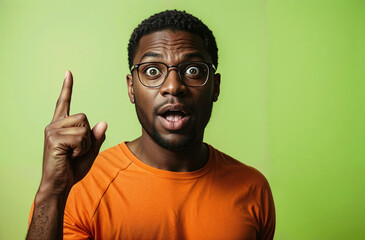 African American man pointing finger up with a surprized facial expression, isolated on a green background