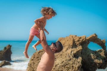 Father And Son Playing On The Beach On A Sunny Day. Smile And Joy Of A Dad And His Son Having Fun On Vacation Or Adventure By The Ocean Enjoying The Weekend.