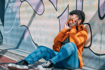 Wall Mural - urban young woman with mobile phone and sunglasses on graffiti wall