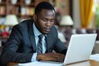 © Yuliia - Beautiful African businessman looking at his daily agenda on a laptop computer.