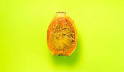 Wall Mural - Prickly pear cactus, halved Opuntia edible fruit macro shot, over green background. Fresh tasty one sweet exotic fruit macro shot. Opuntia ficus indica, top view, flat lay