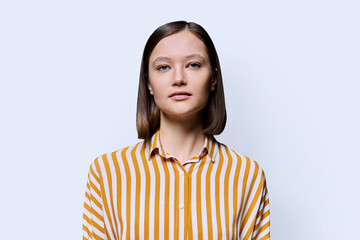 Portrait of young serious woman looking at camera on white background