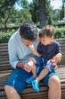 © Westend61 - Son sharing ice cream with father sitting on bench in public park