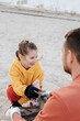 © Westend61 - Father and daughter collecting garbage on beach