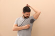 © New Africa - Man in t-shirt before using deodorant on beige background