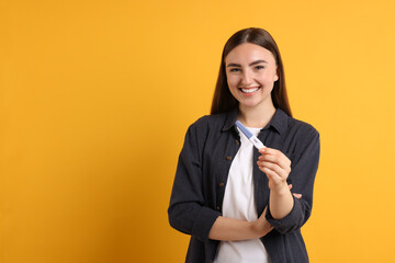 Sticker - Happy woman holding pregnancy test on orange background, space for text