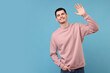 © New Africa - Happy young man waving on light blue background, space for text