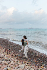 Smiling woman carrying homosexual beloved piggyback on ocean beach