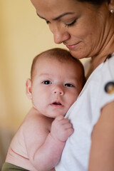 Loving mother hugging newborn at home