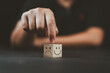 © Nirusmee - Man hand points on a wooden cube with happy smile face on bright side and unhappy face on dark side of wooden block cube for a positive mindset selection. Emotional state and mental health concept.