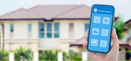 Hand using mobile phone for smart home automation control app over blur house background, Wireless device technology, internet of things, IOT