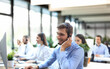 © ty - Portrait of call center worker accompanied by his team. Smiling customer support operator at work.