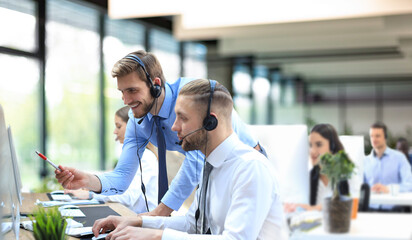 Phone operator working at call centre office helping hiss colleague.