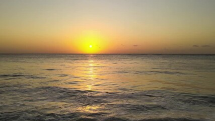 Wall Mural - Low aerial shot overhead the sun setting over the waves crashing