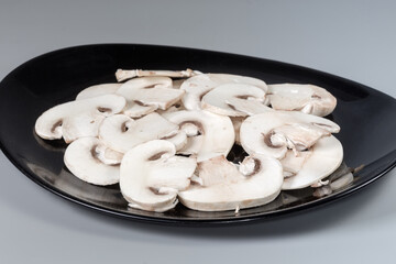 Wall Mural - Sliced raw button mushrooms on black dish close-up