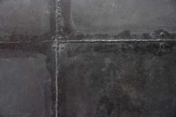 Poster - The image is a close up of a black and grey surface with a lot of texture. welded metal plate background and texture.