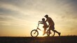 © maxximmm - Happy family. dad teaches his son to ride bike. happy family kid dream concept. silhouette of a child riding a bicycle. silhouette of a father teaching his son lifestyle to ride a bicycle.