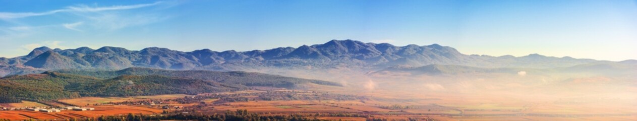 Poster - panorama of romania countryside in morning light. foggy weather. autumnal landscape in mountains. grassy field and rolling hills. rural scenery