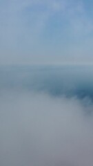 Wall Mural - aerial view. blue sky sun and fog over calm sea. the drone flies over foggy and fluffy clouds. abstr