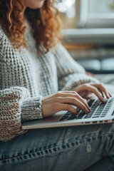 Wall Mural - A woman sits on a couch typing on her laptop, possibly working or studying