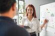 © amnaj - Young businesswoman is using a whiteboard and a tablet to give a presentation to her colleague