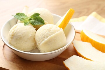 Wall Mural - Scoops of tasty melon sorbet with mint in bowl and fresh fruit on table, closeup