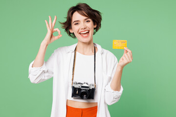 Wall Mural - Traveler smiling happy woman wears casual clothes hold passport ticket card show ok okay isolated on plain green background. Tourist travel abroad in free time rest getaway. Air flight trip concept.