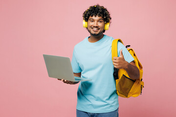 Wall Mural - Young Indian boy IT student wears blue t-shirt casual clothes headphones backpack bag work use laptop pc computer listen music isolated on plain pink background High school university college concept