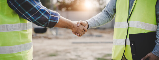 Wall Mural - construction worker and contractor. Client shaking hands with team builder in the factory construction site.