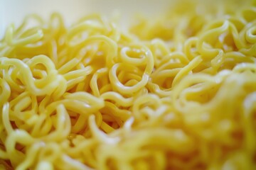 Close up of instant yellow ramen noodles in a cup, ready to be cooked or eaten. Packaged convenience food.