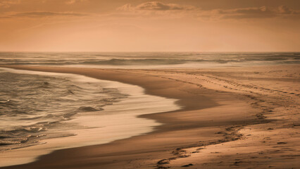 Wall Mural - A lone person walking along the beach at sunset, AI