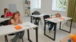© kinomaster - Junior school boys and girls sit in room in astronomy class. Female teacher reads test papers, kids bored and napping. Modern education concept.
