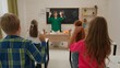 © kinomaster - Junior school boys and girls sit in room in astronomy class. Female teacher and kids doing warm up exercises. Modern education concept.