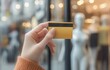 © Ekkarat_Studio - A hand holding a credit card in front of a store window with mannequins