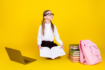 Poster - Full length photo of small schoolgirl online lesson read book look empty space dressed stylish uniform isolated on yellow color background