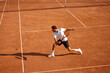 © master1305 - Young man, tennis player showing endurance and strength during intensive training on clay court. Man practicing for upcoming game. Concept of sport, competition, active and healthy lifestyle