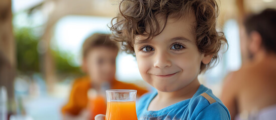 Cute little boy holding orange juice in his hand