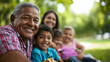 © mittpro - A happy multigenerational family enjoying a picnic in a lush green park with children playing and grandparents smiling, highlighting the warmth and unity of family bonds