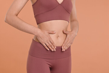 Poster - Healthy digestion. Woman touching her belly on beige background, closeup