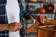 © New Africa - Man repairing wooden stool with hammer indoors, closeup