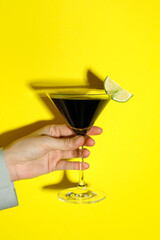 Wall Mural - Woman with glass of refreshing cocktail on yellow background, closeup