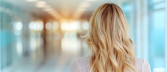 a woman's back as she walks down a hallway, heading towards another building