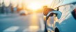 © AlgoCreative - Close-up of an electric vehicle charging with a sunset in the background, emphasizing sustainable energy and modern transportation.