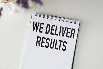 We Deliver Results. text on white paper, on a notepad, on white background